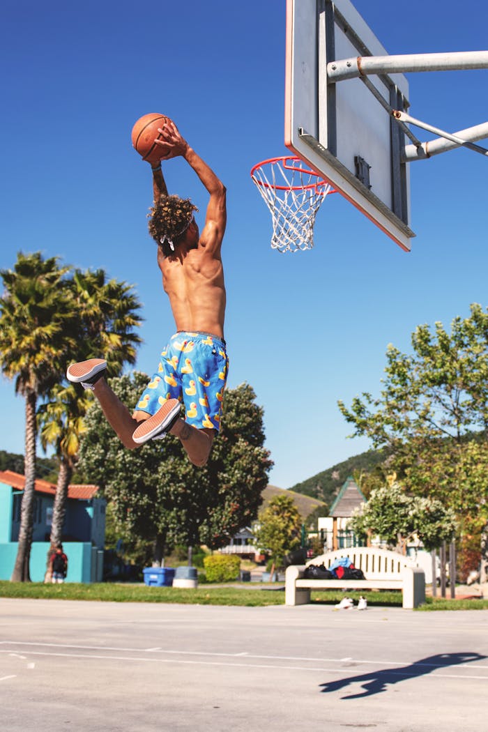 Crafting Captivating Headlines: Your awesome post title goes here Shirtless man performing a basketball dunk at outdoor court in summer.